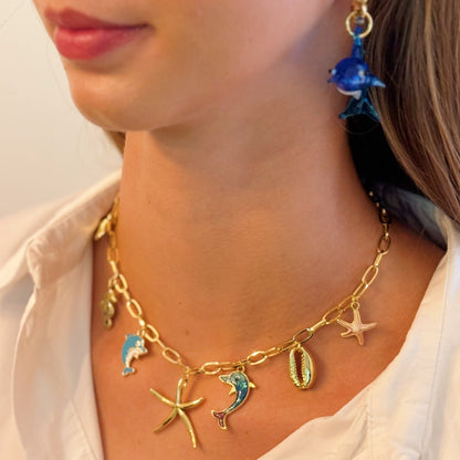 Gold necklace with sea-themed charms worn by a person