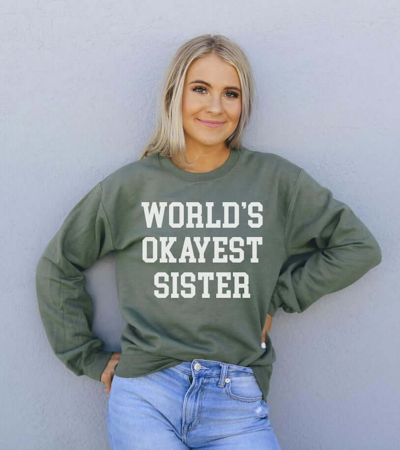 Model wearing the World's Okayest Sister Sweatshirt in green, showcasing its comfortable, stylish design.
