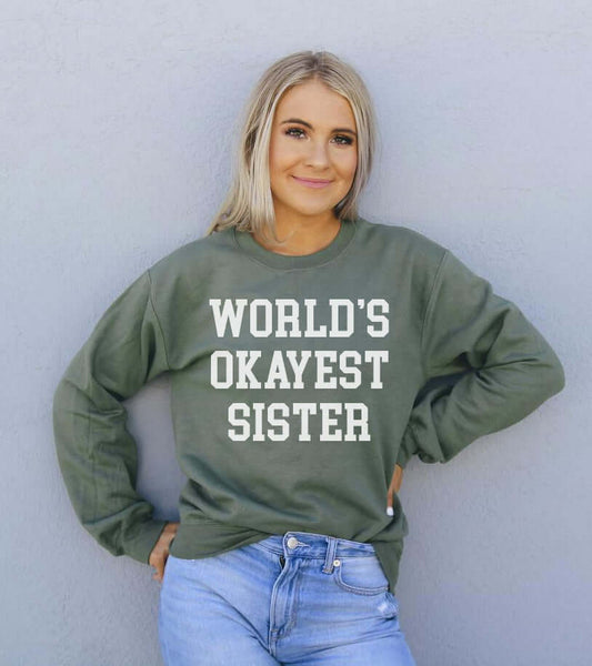 Model wearing the World's Okayest Sister Sweatshirt in green, showcasing its comfortable, stylish design.